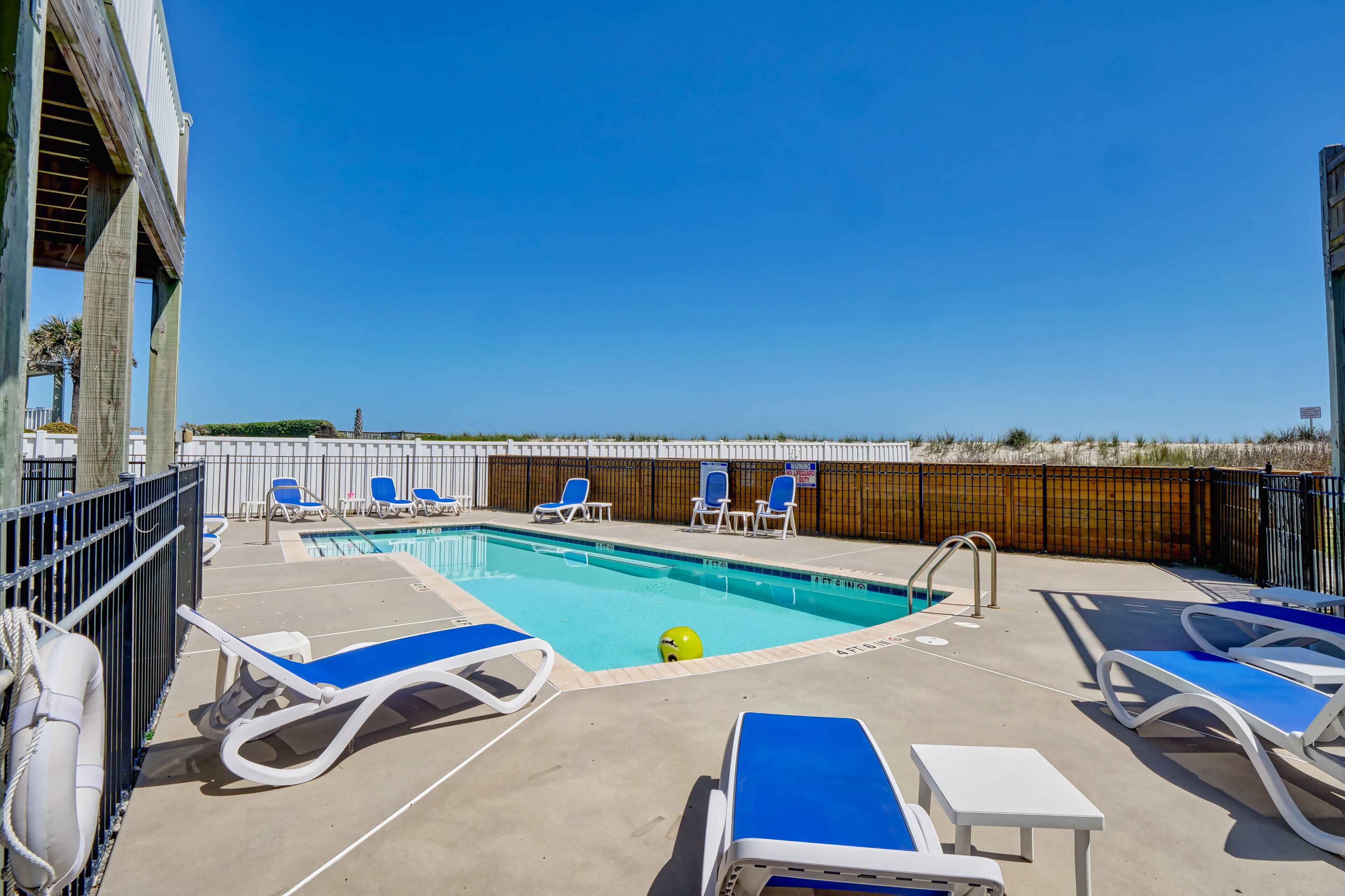 Ein Poolbereich mit Liegestühlen und blauem Himmel.