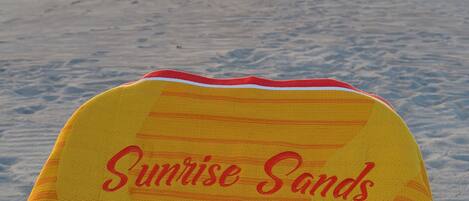A beach scene with a chair labeled "Sunrise Sands" and a sunset in the background.