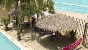 A poolside area with a thatched umbrella, lounge chairs, and potted plants. - Excellent beach apartment with excellent amenities (Provincia de Panamá Oeste)