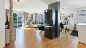 Una cocina moderna con un refrigerador negro grande, piso de madera y un comedor con sillas.
