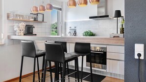 Una cocina moderna con barra, electrodomésticos de acero inoxidable e iluminación colgante.