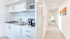 Una cocina moderna con armarios blancos, una estufa a gas, un microondas y una cafetera.