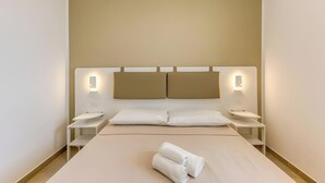 Een hotelkamer met een groot bed, twee nachtkastjes en wandlampen.