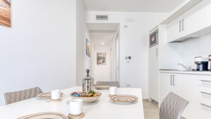 Een moderne keuken met witte kasten, een eettafel gedekt met borden, bekers en een decoratieve schaal.