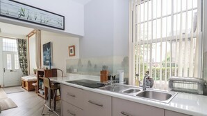 Uma cozinha moderna com uma janela grande, fogão embutido e um espaço de jantar com cadeira e mesa.