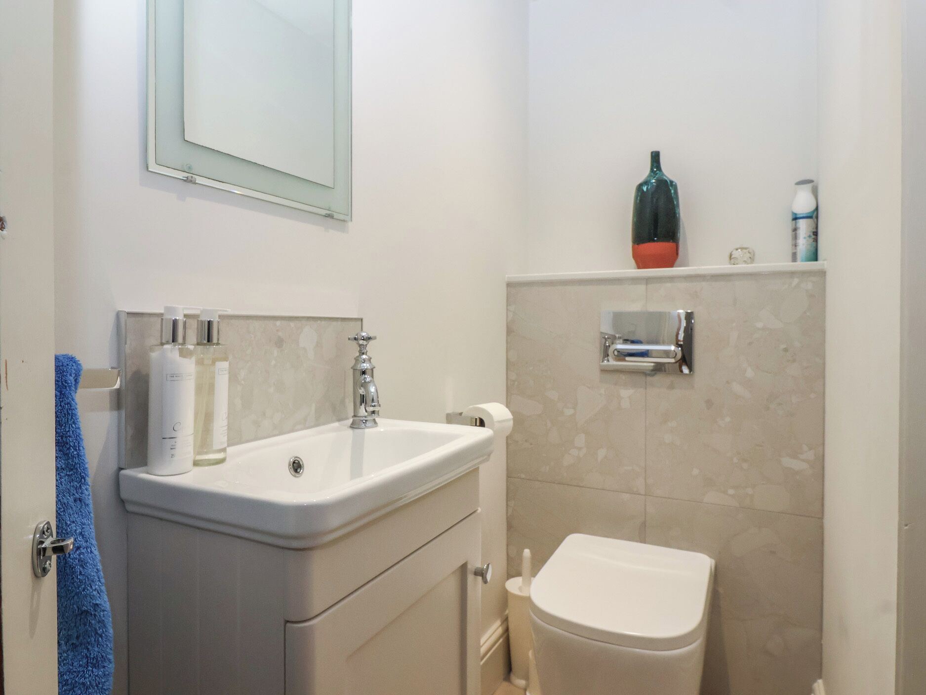 Une salle de bain équipée d’un lavabo, d’un miroir, de toilettes et d’une étagère contenant des articles de toilette.