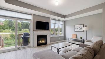 Una sala de estar moderna con chimenea, ventanas amplias y un televisor de pantalla plana.