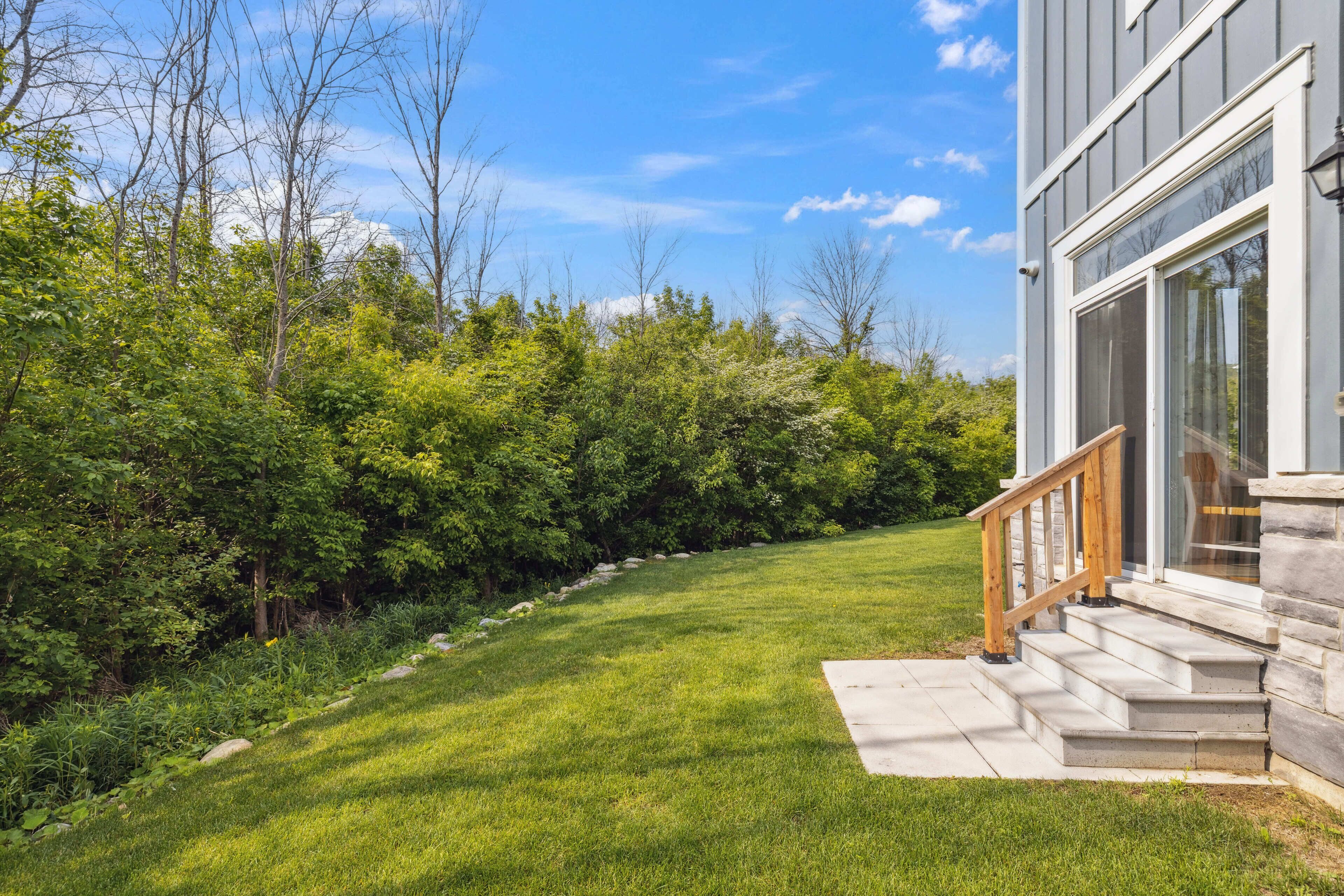 A well-maintained lawn with a stone staircase leading to a modern building with large windows.