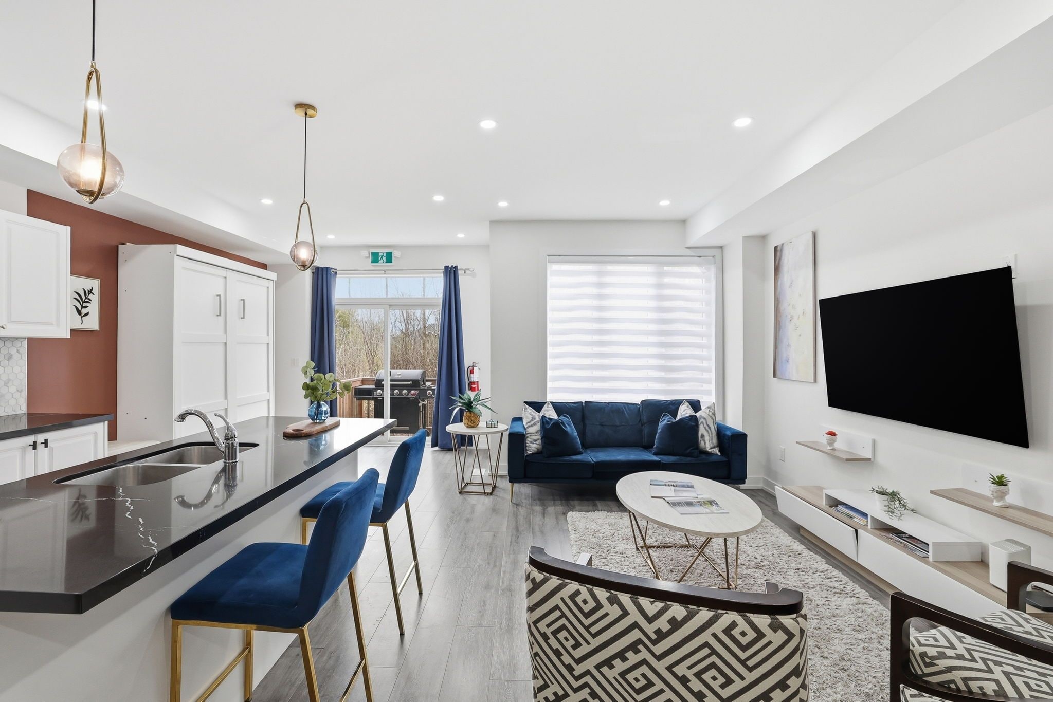 A modern apartment with a kitchen, dining area, living room, and a TV mounted on the wall.