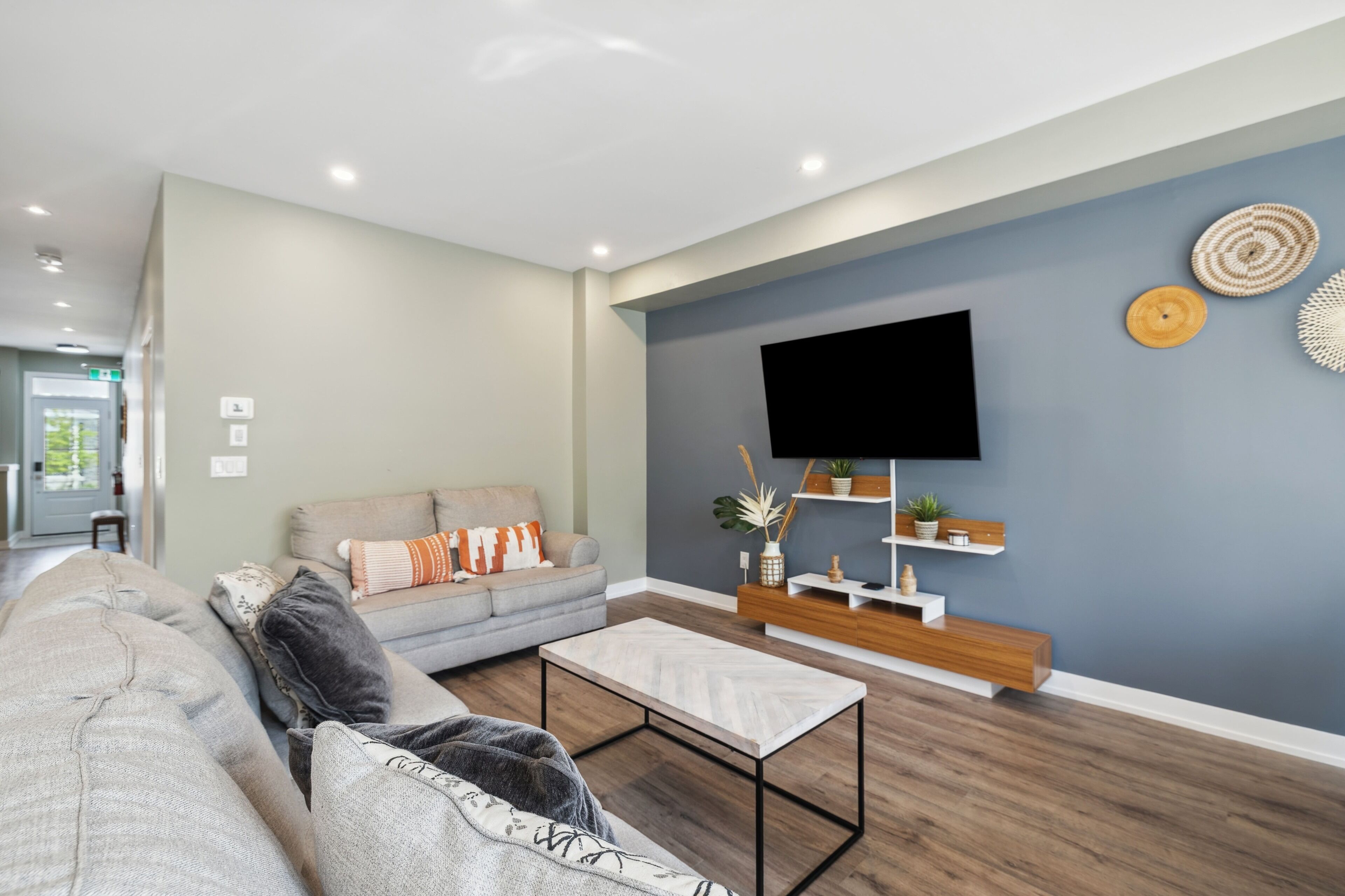 A modern living room with a grey sofa, a coffee table, and a TV mounted on the wall.