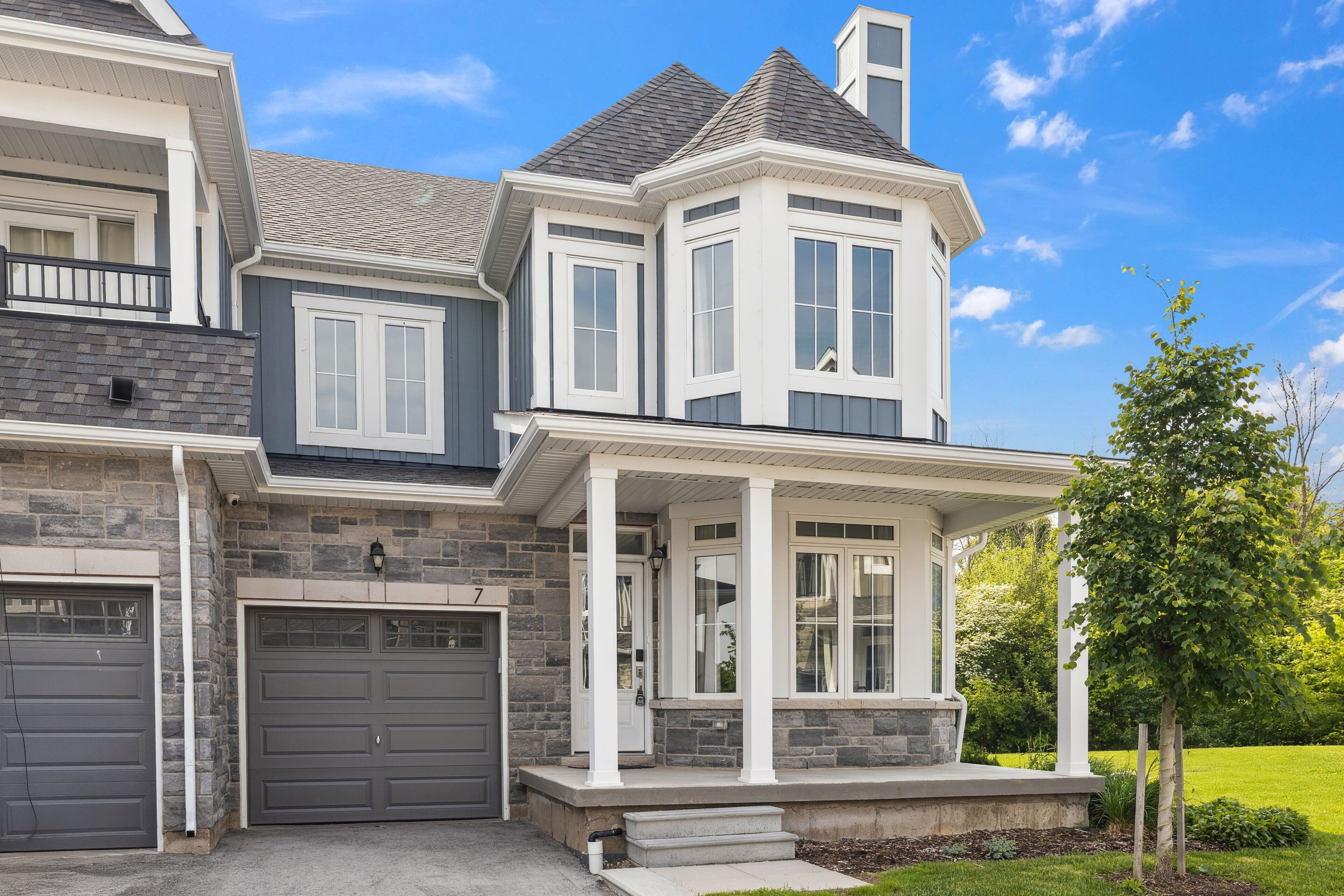 A two-story house with a stone facade, a large garage, and a covered front porch.