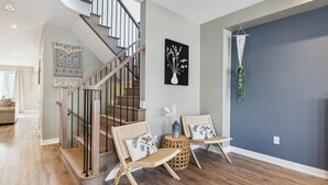 A modern interior with a wooden staircase, wicker chairs, and a blue accent wall. - Crosswinds Townhomes (The Blue Mountains)