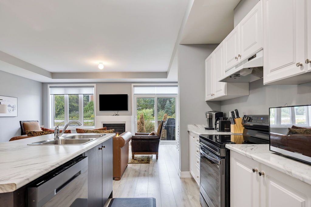 A modern kitchen with a large island, built-in appliances, and a flat-screen TV.