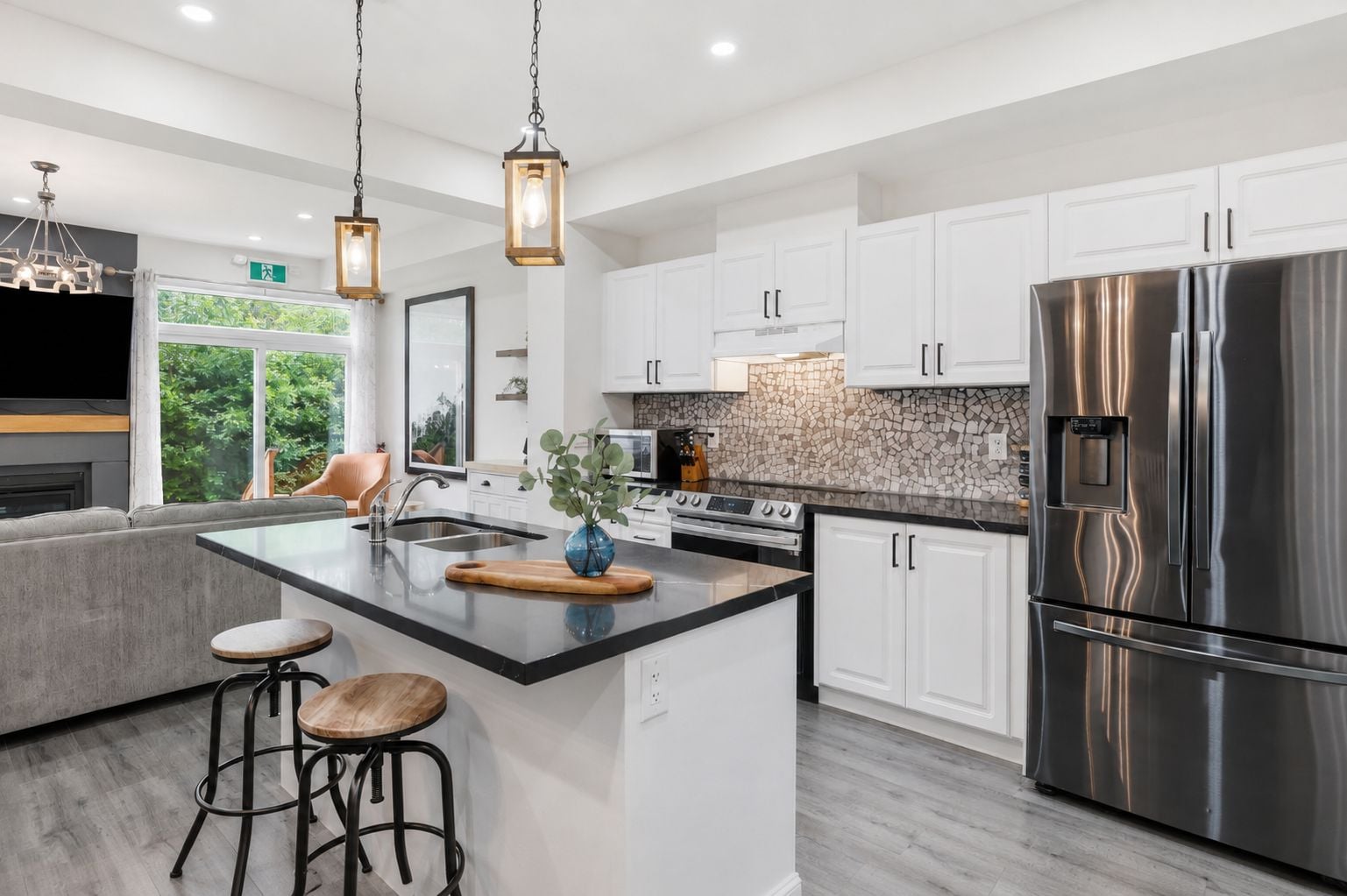 A modern kitchen with white cabinetry, a stainless steel refrigerator, and a central island with stools.