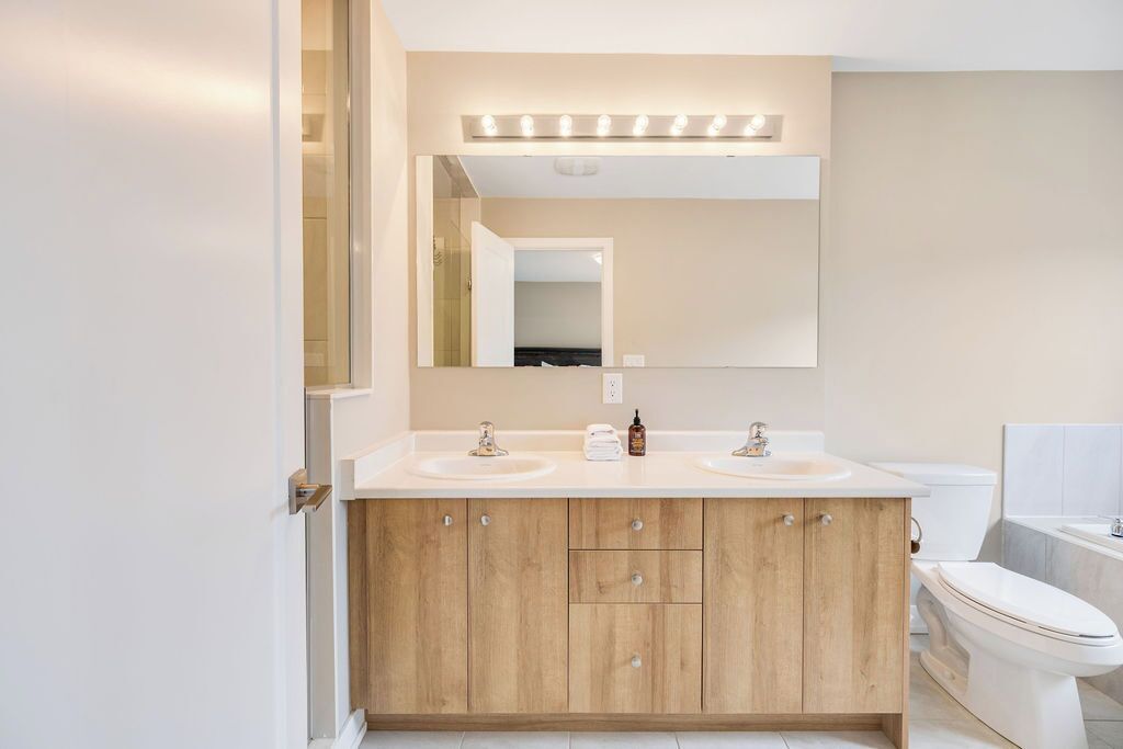 Ein modernes Badezimmer mit zwei Waschbecken, einem großen Spiegel und einer Toilette.