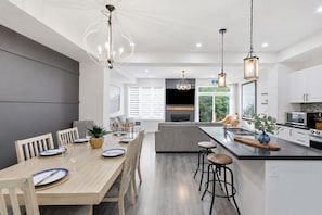 A modern kitchen with a central island, bar stools, and pendant lighting. - Crosswinds Townhomes (The Blue Mountains)