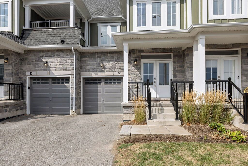A multi-story residential building with two garages, stone exterior, and a front porch with a black railing.