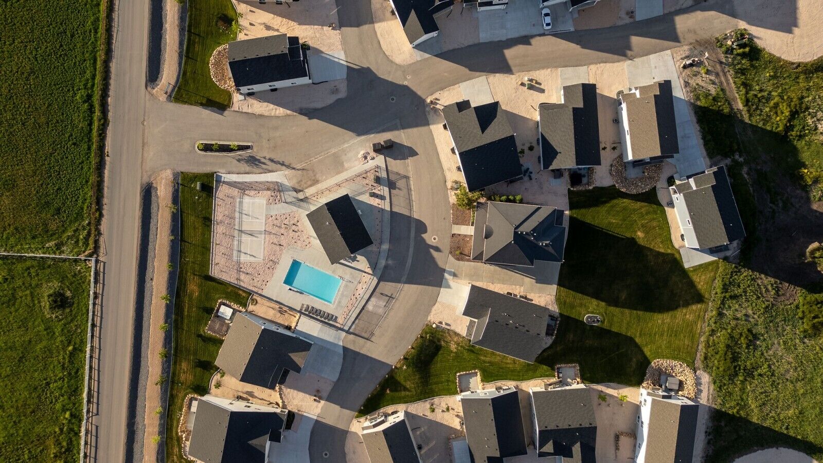 Une vue aérienne d’un quartier résidentiel avec plusieurs maisons, une piscine et une route.