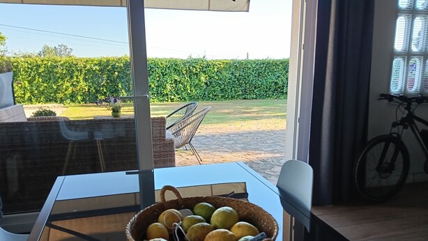 A dining area with a table, chairs, and a basket of fruits.