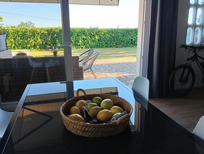 A dining area with a table, chairs, and a basket of fruits. - House near Cayón beach, razo and baldayo.ideal for group of people. (A Coruña)