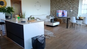 A modern living room with a white sofa, a coffee table, and a TV in the background.