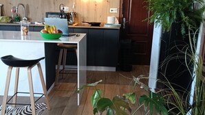 A modern kitchen with wooden cabinetry, a central island, and a variety of plants.