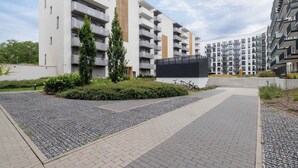 Un edificio de apartamentos moderno con varios balcones, un patio ajardinado y un aparcamiento para bicicletas.