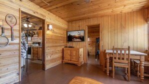 Un interno in legno con zona pranzo, televisione e cucina visibile attraverso una porta aperta.