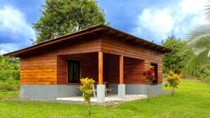 A wooden cabin with a porch, surrounded by greenery and a clear sky. - Private River - Nature Cabin Near La Fortuna (La Fortuna,)