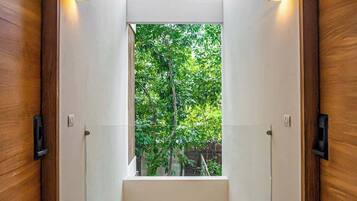 A hallway with a bench, wooden doors, and a view of greenery outside.