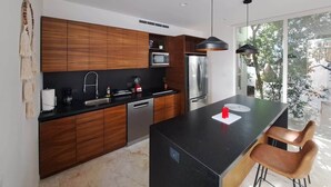 A modern kitchen with wooden cabinets, a black countertop, stainless steel appliances, and a large island with bar stools.