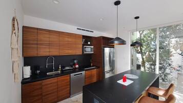 A modern kitchen with wooden cabinets, a black countertop, stainless steel appliances, and a large island with bar stools.