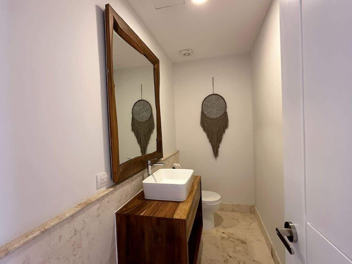 A bathroom with a wooden vanity, a white sink, a mirror, and a toilet.