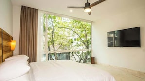 A bedroom with a bed, a ceiling fan, a TV, and a window with a view of trees. - 3 Bedrooms Penthouse-Private Pool-Free parking (Tulum)
