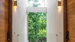 A hallway with wooden doors, a bench, and a view of greenery outside. - 3 Bedrooms Penthouse-Private Pool-Free parking (Tulum)