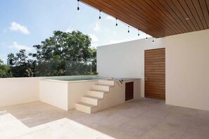 A modern outdoor patio with a wooden staircase leading to a pool, surrounded by white walls and a wooden door. - 3 Bedrooms Penthouse-Private Pool-Free parking (Tulum)