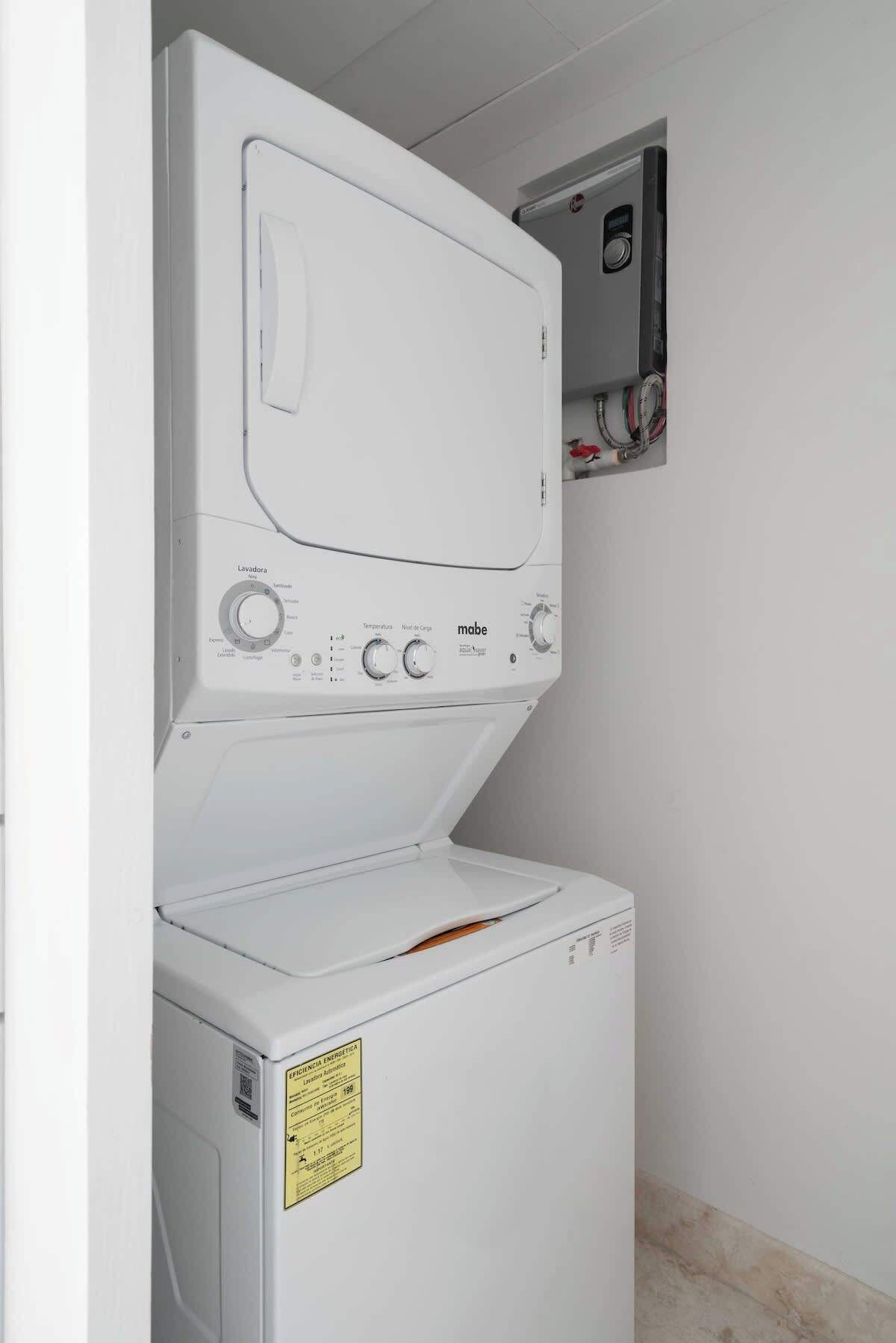A laundry room with a front-loading washer and dryer stacked vertically.