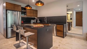 A modern kitchen with a central island, stainless steel appliances, and pendant lighting.
