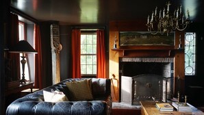 Ein gemütliches Wohnzimmer mit Ledersofa, Kamin und einer Deckenleuchte.