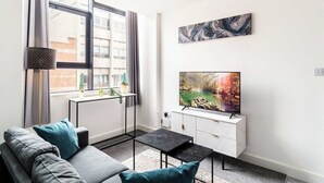 A modern living room with a sofa, a coffee table, a TV, and artwork on the wall.