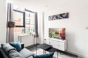 Una sala de estar moderna con un sofá, una mesa de centro, un televisor y obras de arte en la pared.