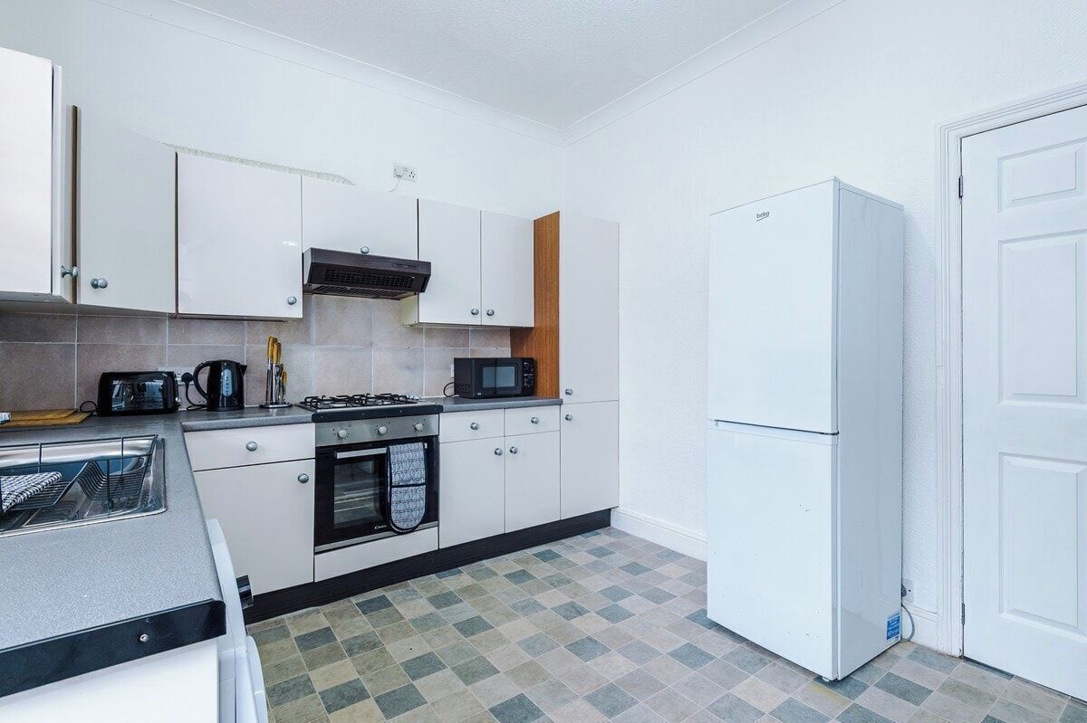 A compact kitchen with white cabinets, a microwave, a stove, and a refrigerator.
