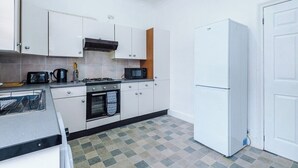 A compact kitchen with white cabinets, a microwave, a stove, and a refrigerator. - Preston PR2 Home | Ashton-on-Ribble | Parking (Lancashire)