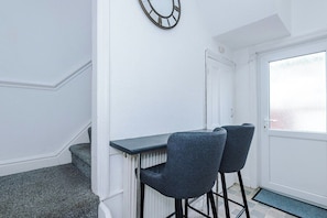 A room with a white door, a radiator, two grey chairs, and a black wall clock.