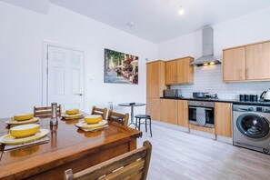 Una cocina moderna con armarios de madera, horno empotrado y lavadora.
