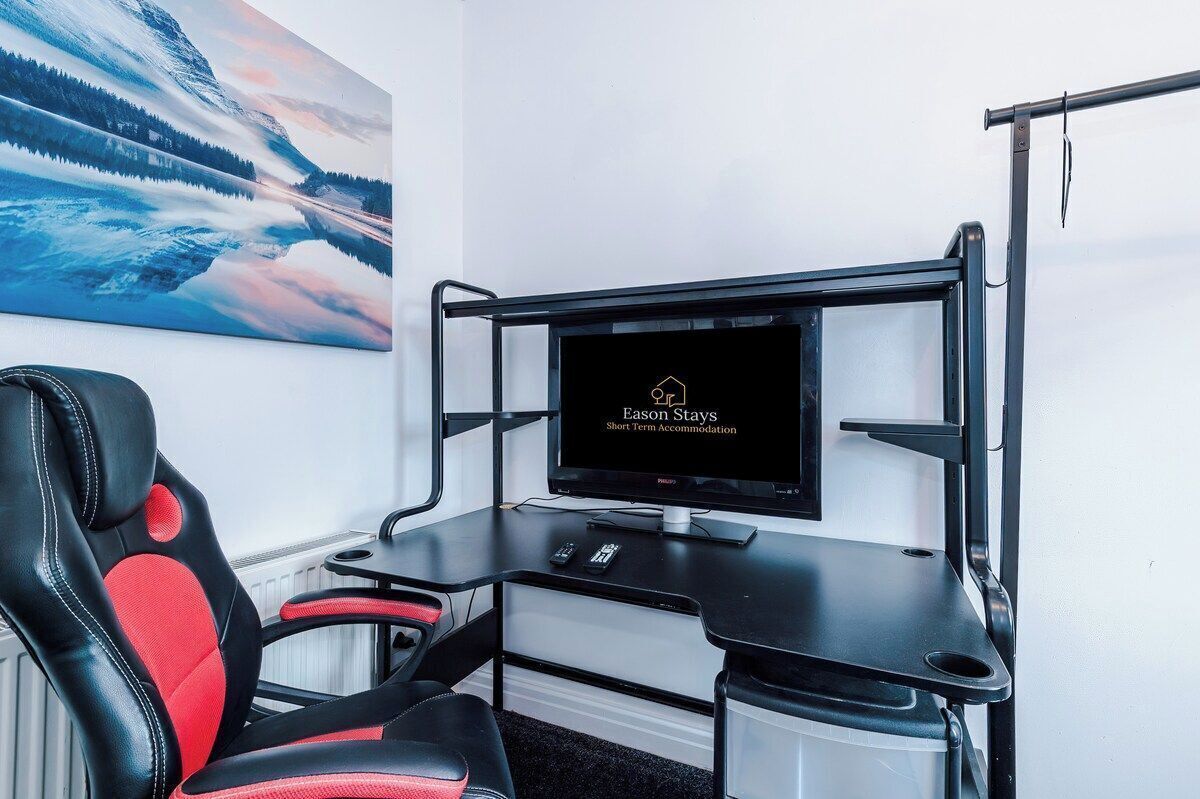 Un espace de travail compact comprenant un bureau, une chaise et un téléviseur affichant la mention « Eason Stays : hébergement de courte durée ».
