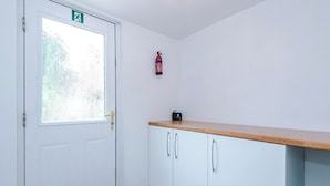 A white door with a frosted glass window, a fire extinguisher mounted on the wall, and a wooden countertop with cabinets. - 15%OFF|Stay7PayLess|Business|Parking|WiFi|Sleeps7 (Lancashire)