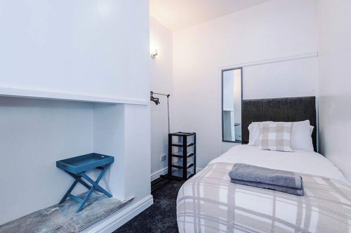 Une chambre d’hôtel avec un lit, une table de chevet, un miroir et une petite étagère.