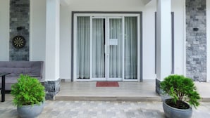 A modern entrance with a glass door, a stone wall, and a potted plant. - Kampot Origin Guesthouse (Kampot)