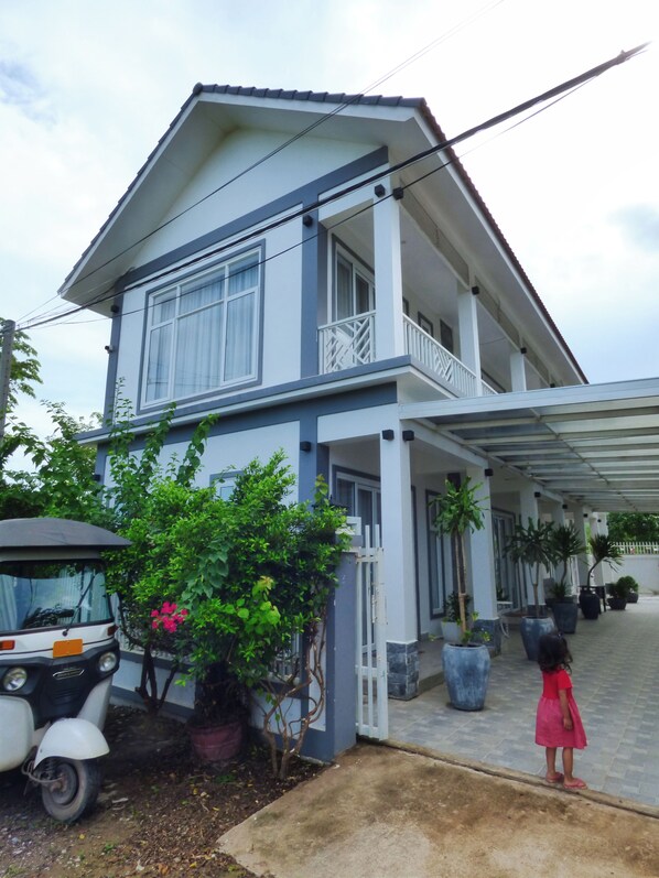 A two-story house with a covered porch and potted plants.